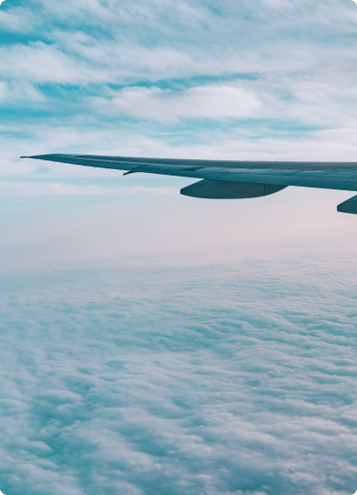 Vista aérea mostra asa de avião sobre um mar de nuvens ao entardecer.