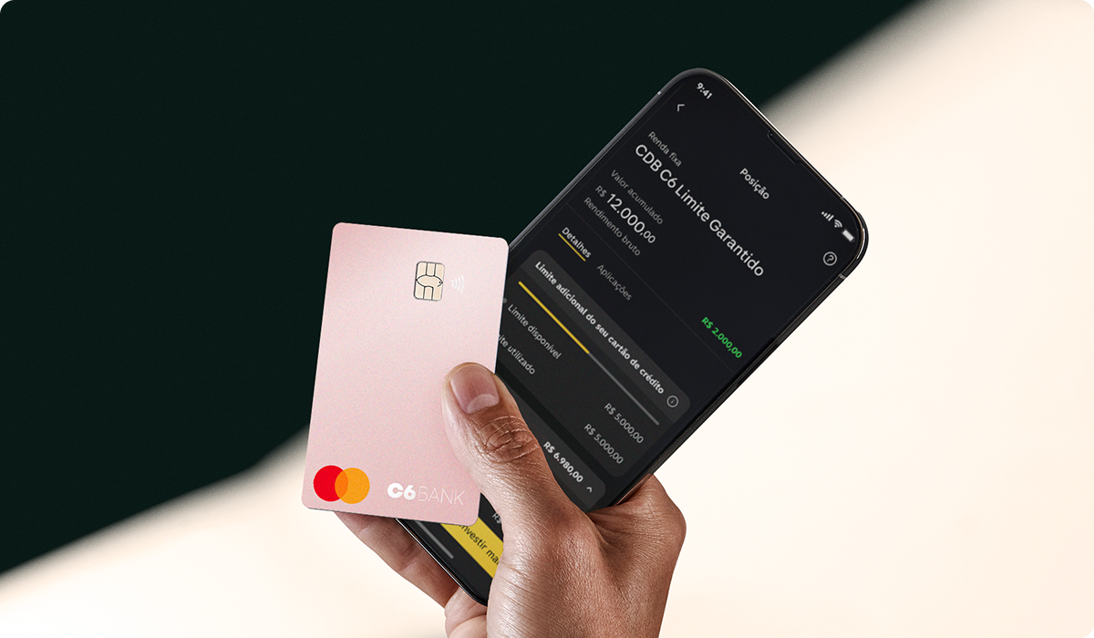 Cartão C6 Pink é segurado junto a celular com app do C6 Bank aberto, mostrando limite garantido.