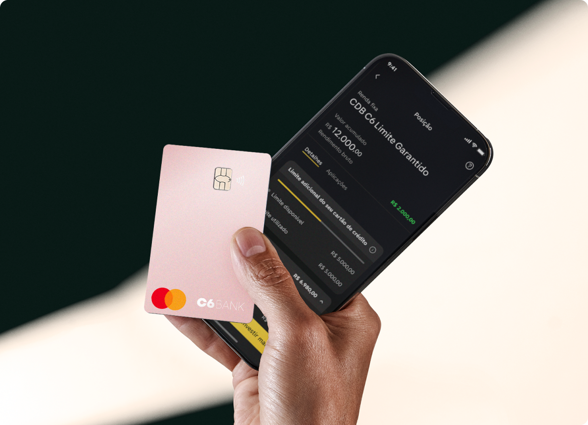 Cartão C6 Pink é segurado junto a celular com app do C6 Bank aberto, mostrando limite garantido.