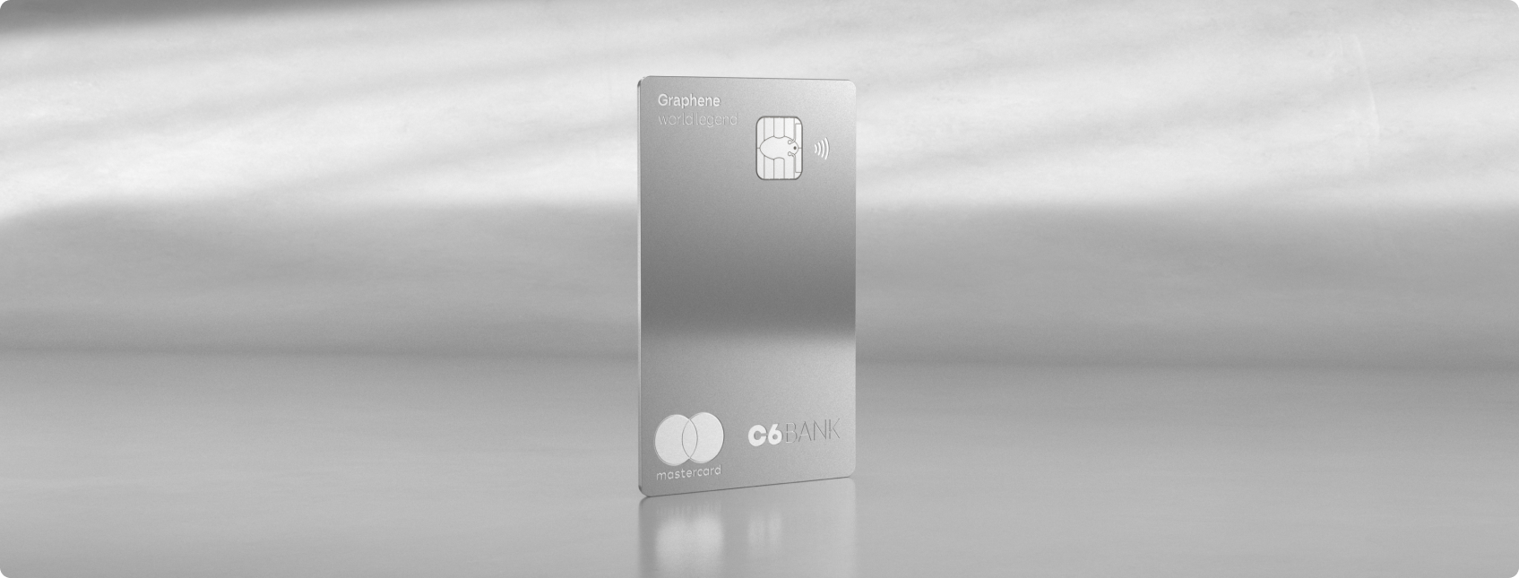 Cartão C6 Graphene World Legend Mastercard prateado, na vertical, sobre superfície reflexiva, com chip, símbolo de aproximação e logotipos da Mastercard e do C6 Bank.
