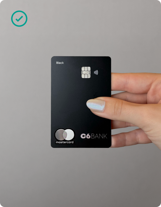 Mão feminina segurando o cartão do C6 Bank no meio, em formato de pinça,