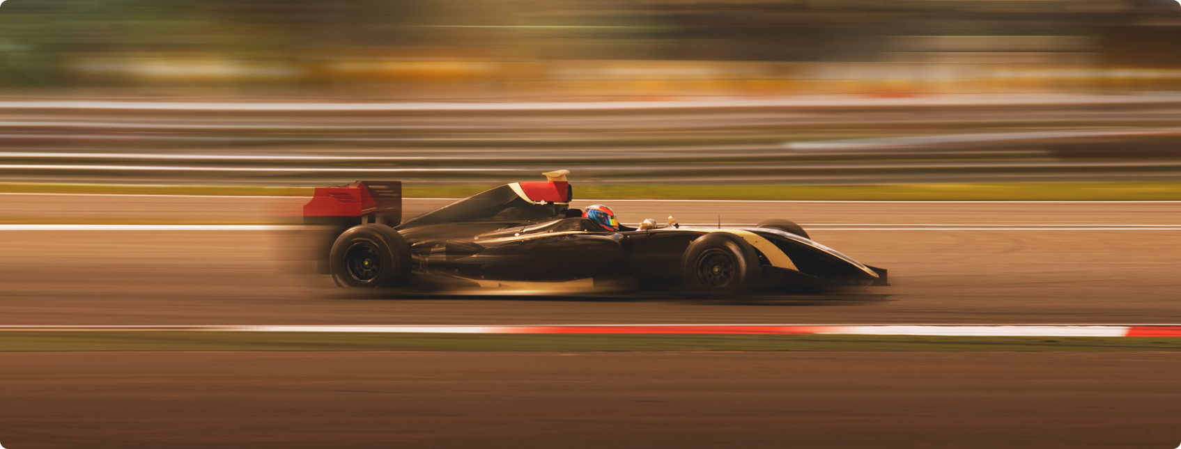 Carro de Fórmula 1 preto corre em pista com fundo desfocado.
