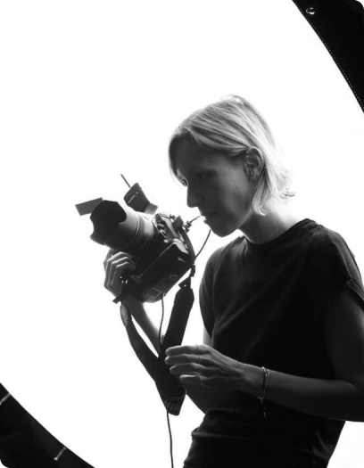 Nicole Heiniger segura câmera fotográfica em retrato preto e branco.