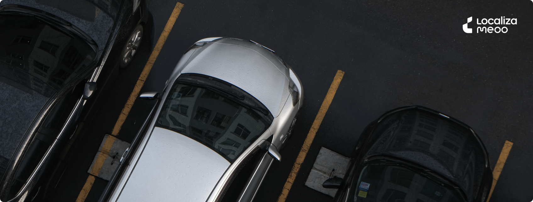Fotografia de 3 vagas de um estacionamento, com carros nas cores preta e cinza. Na parte superior, logo da Localiza Meoo.