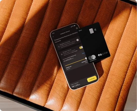 Celular com app do C6 Bank e cartão C6 Mastercard Black sobre assento caramelo, exibindo troca de pontos por dinheiro.