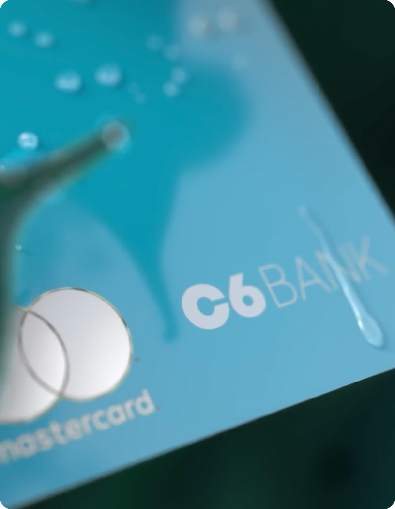 Fotografia do cartão C6 Acqua, com gotas escorrendo sobre ele.