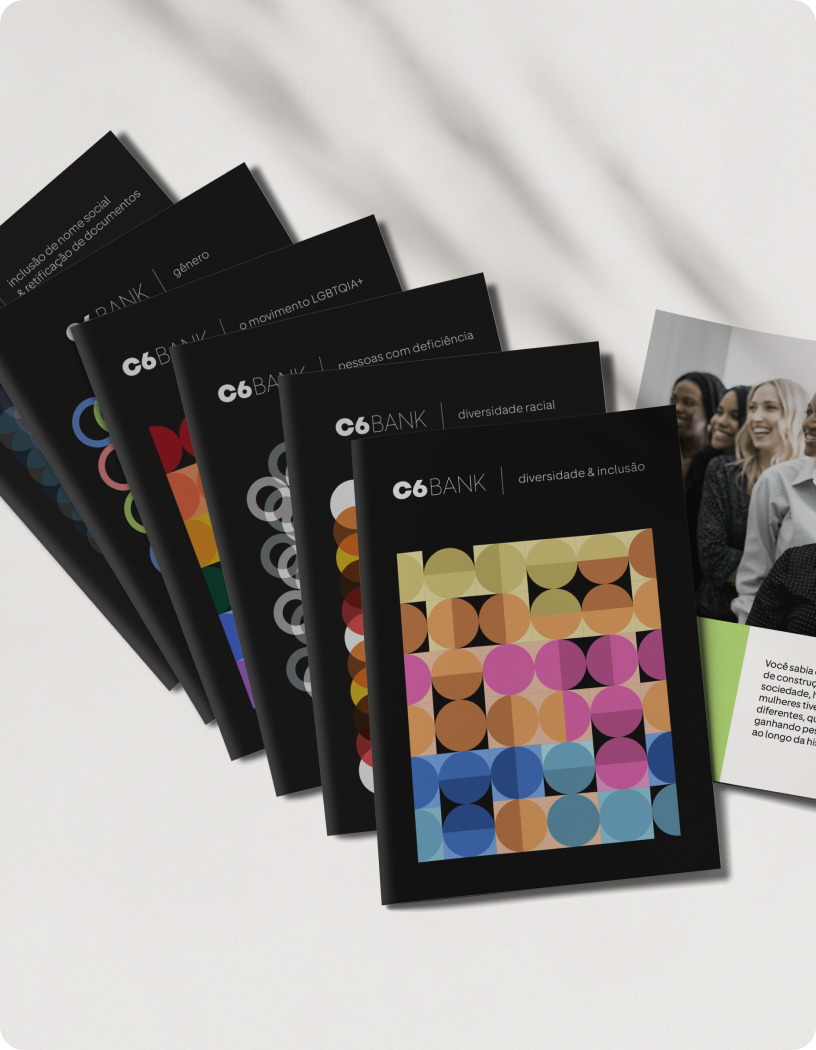 Foto de cartilhas do C6 Bank sobre diversidade e inclusão, com fundo escuro e ilustrações coloridas.