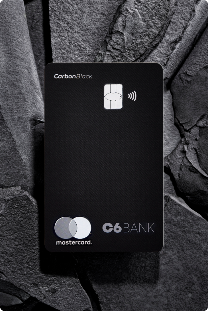 Cartão C6 Carbon Mastercard Black sobre pedras escuras, com design fosco e logos do C6 Bank e Mastercard.