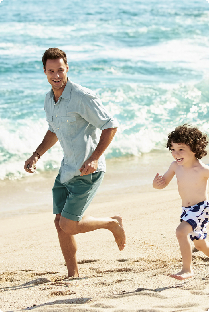 Fotografia de pai e filho correndo em uma praia.