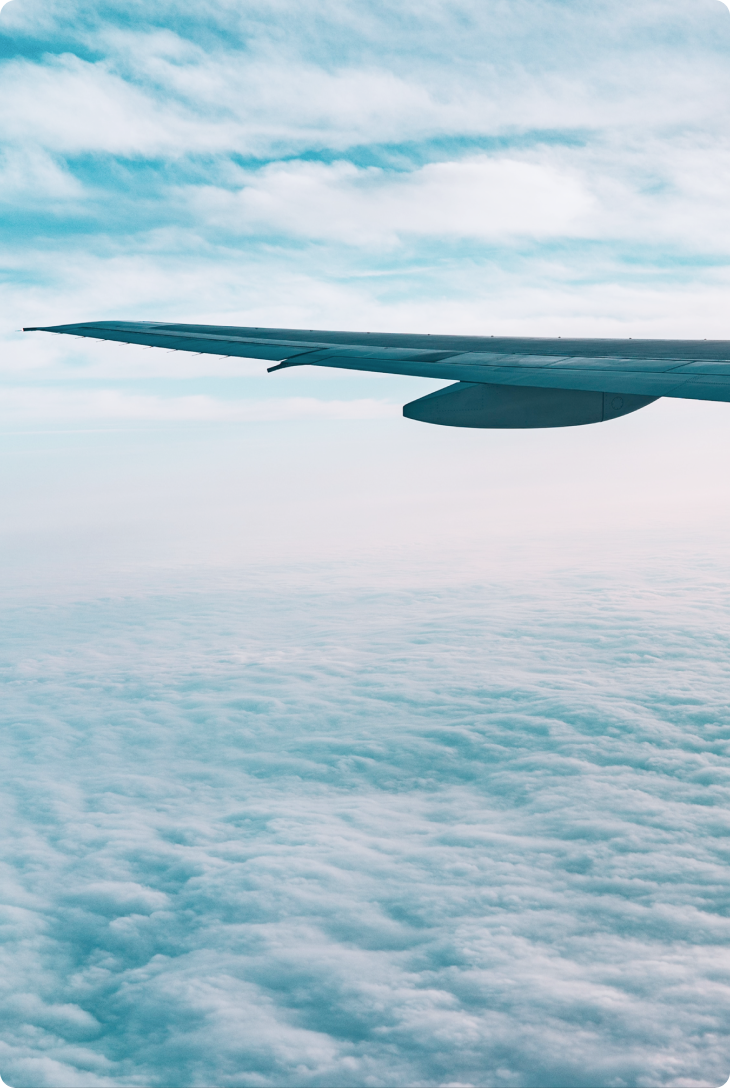 Fotografia de asa de avião em meio as nuvens.