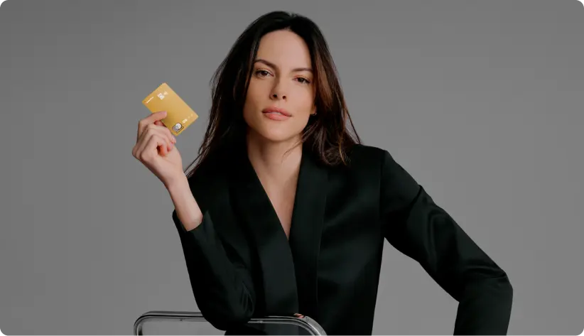 Mulher de preto segura um Cartão C6 Bank e olha para a câmera.