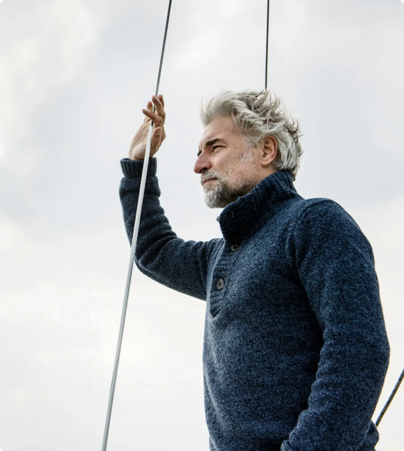 Homem de suéter azul observa o horizonte enquanto segura um cabo.
