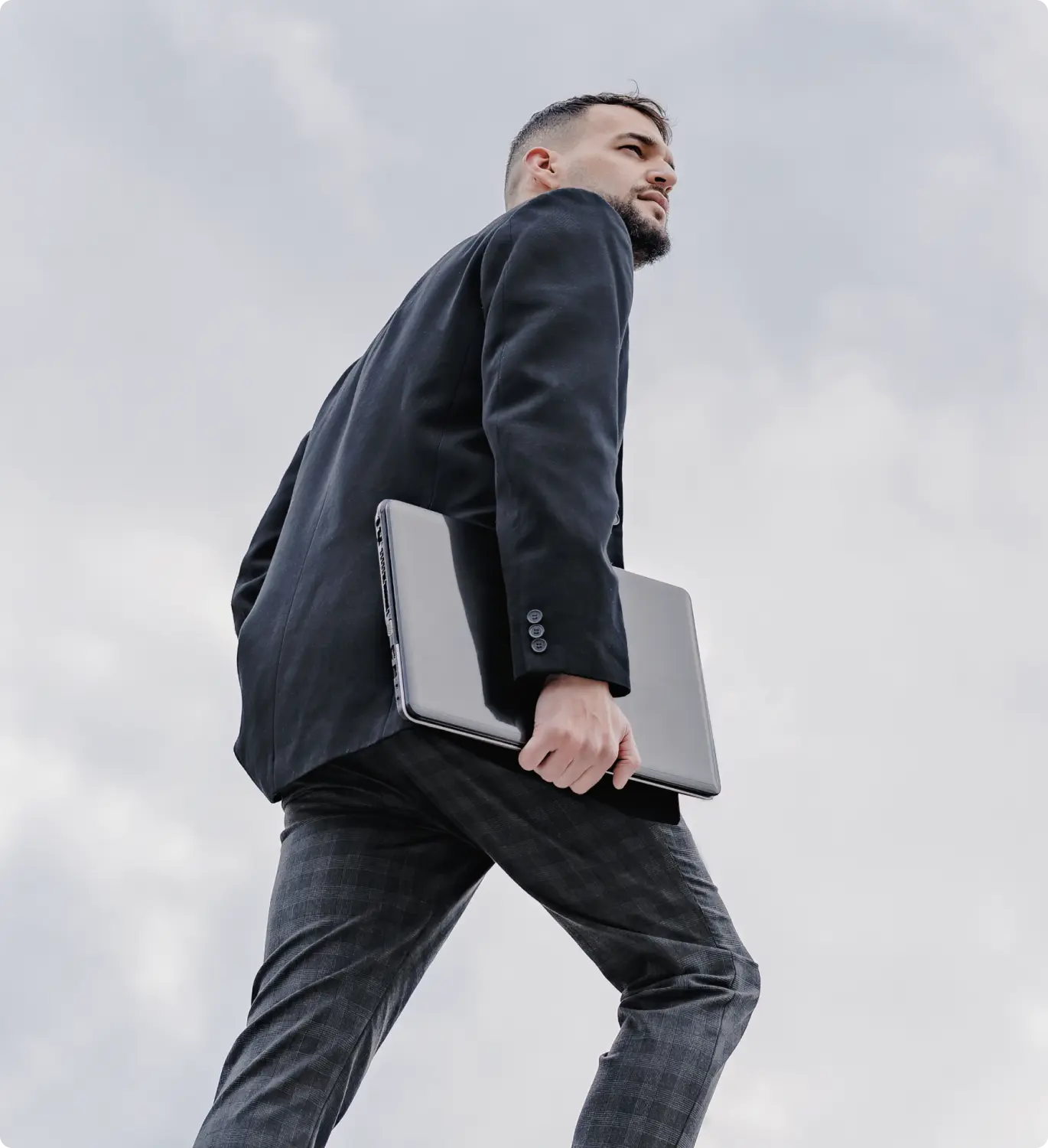 Foto de homem de terno segurando um notebook em seu braço direito