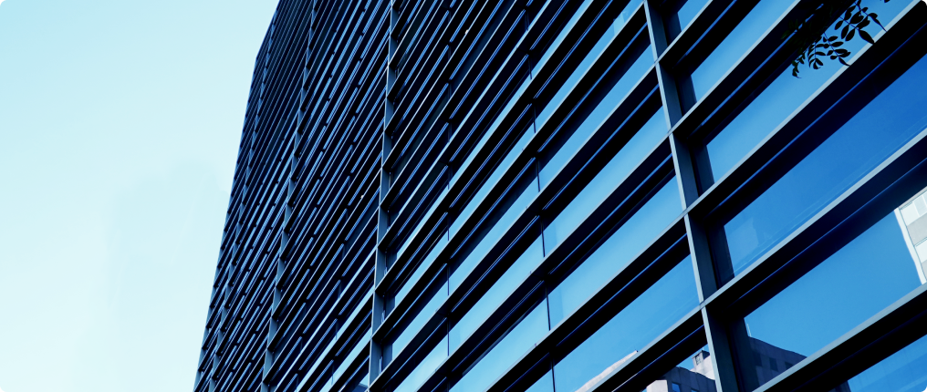 Fachada envidraçada de um prédio com reflexo do céu azul.