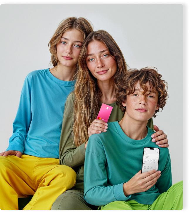 Três jovens com roupas coloridas seguram um Cartão C6 Yellow rosa e um celular com o app do C6 Bank.