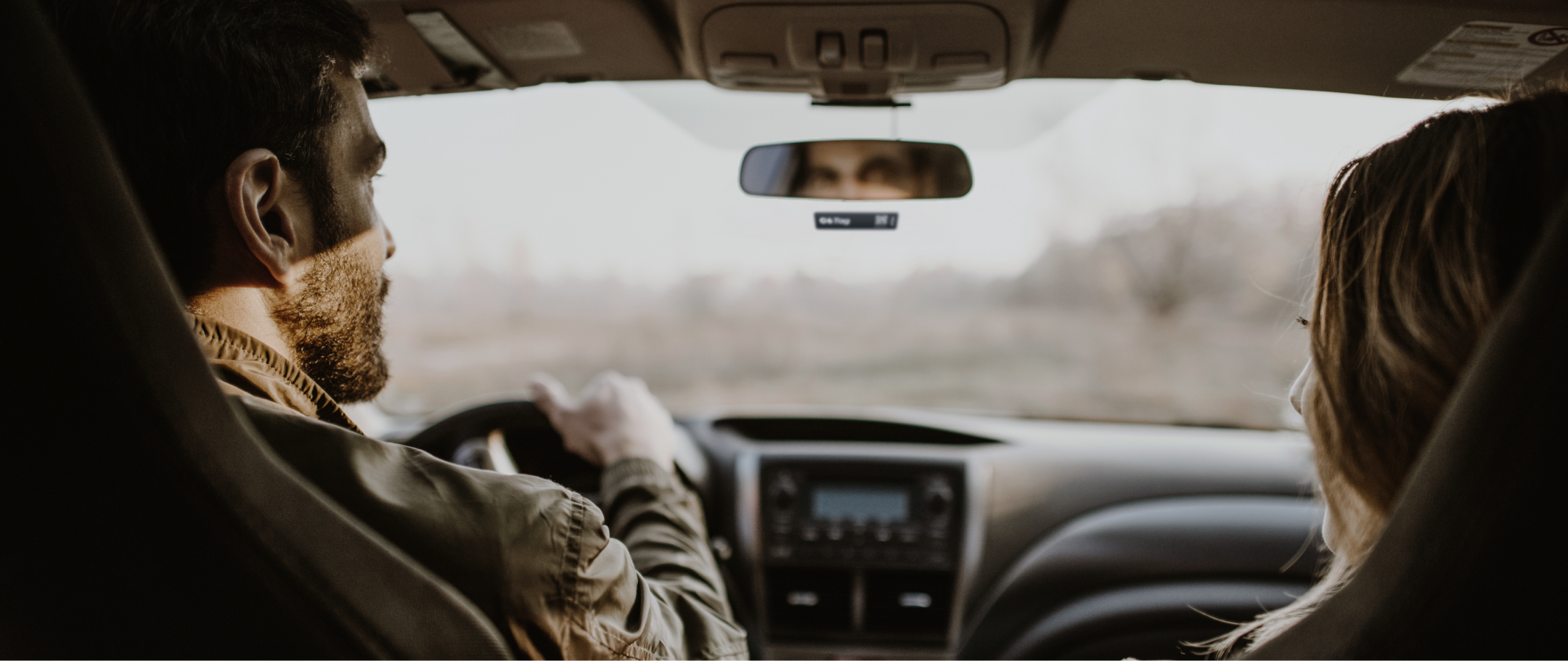Fotografia dentro de um carro com homem no volante e mulher loira no passageiro, com o C6 Tag no vidro