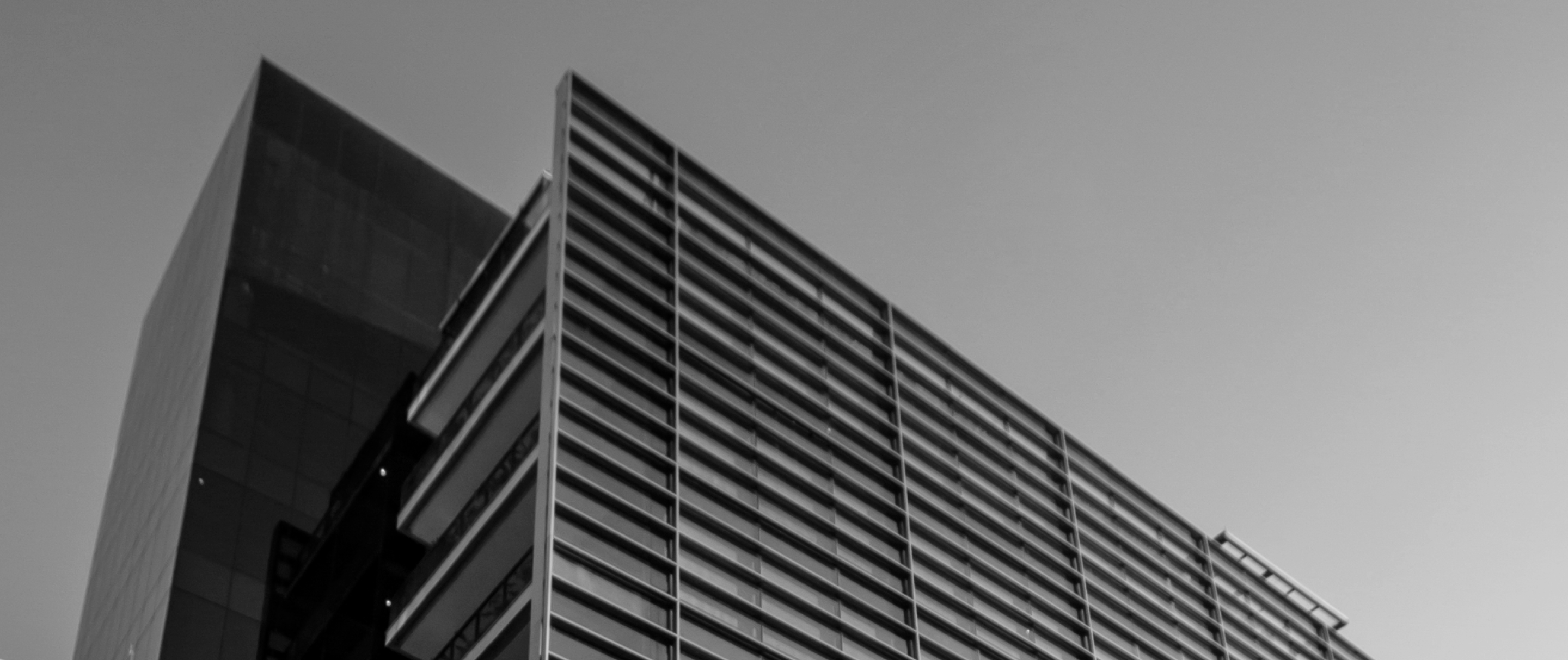Sede C6 Bank: Prédio moderno em preto e branco com linhas horizontais e céu ao fundo.