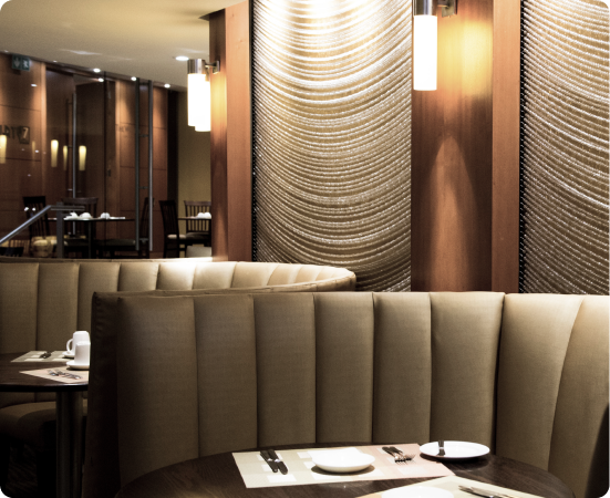 Restaurante elegante com mesas postas e sofás arredondados.