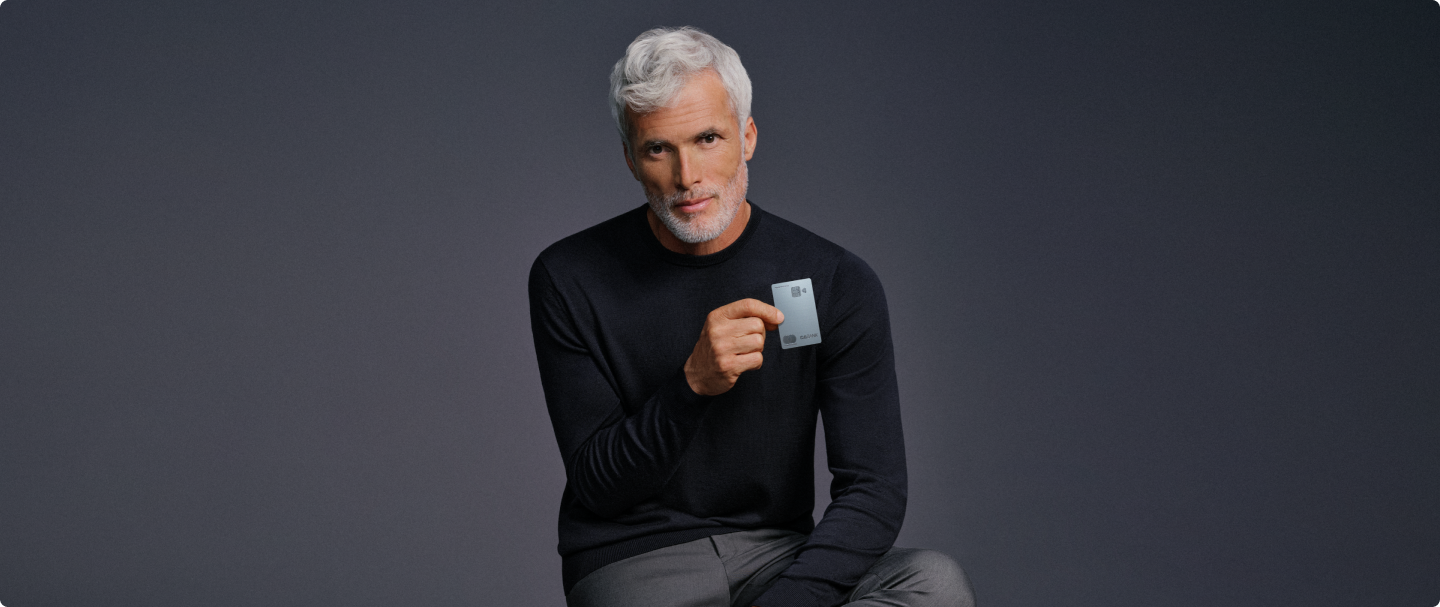 Homem segura o Cartão C6 Graphene com fundo neutro; visual sofisticado e elegante.