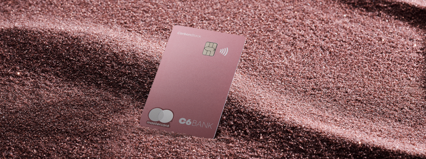 Cartão de Crédito C6 Carbon Mastercard Black na cor pink sobre fundo rosa