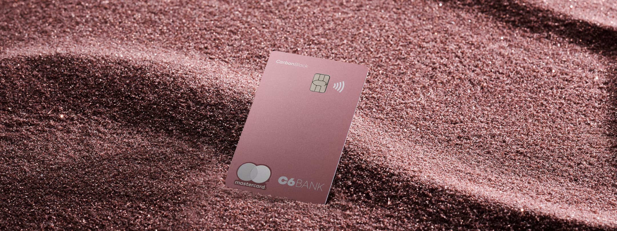 Cartão de Crédito C6 Carbon Mastercard Black na cor pink sobre fundo rosa