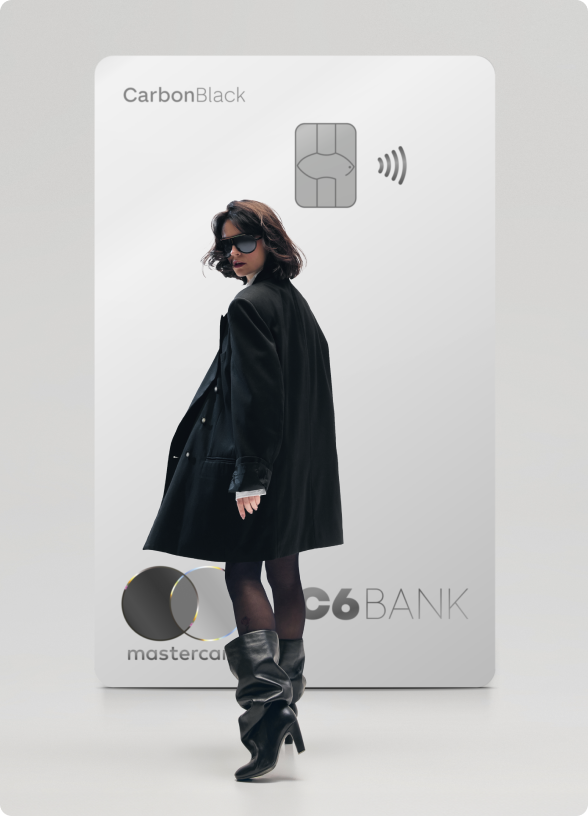 Mulher de preto caminha à frente de um Cartão C6 Carbon Mastercard Black branco em tamanho ampliado, sobre fundo claro.