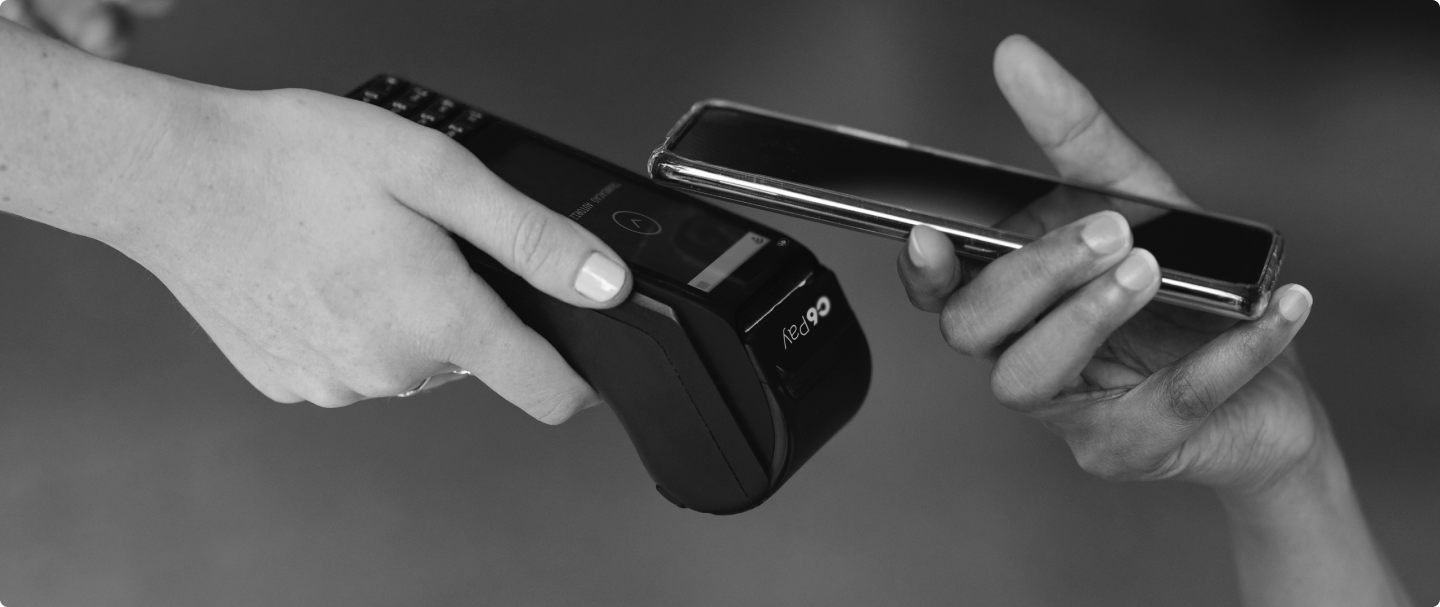 Foto em preto e branco de pagamento com celular por aproximação em uma maquininha de cartão C6 Pay