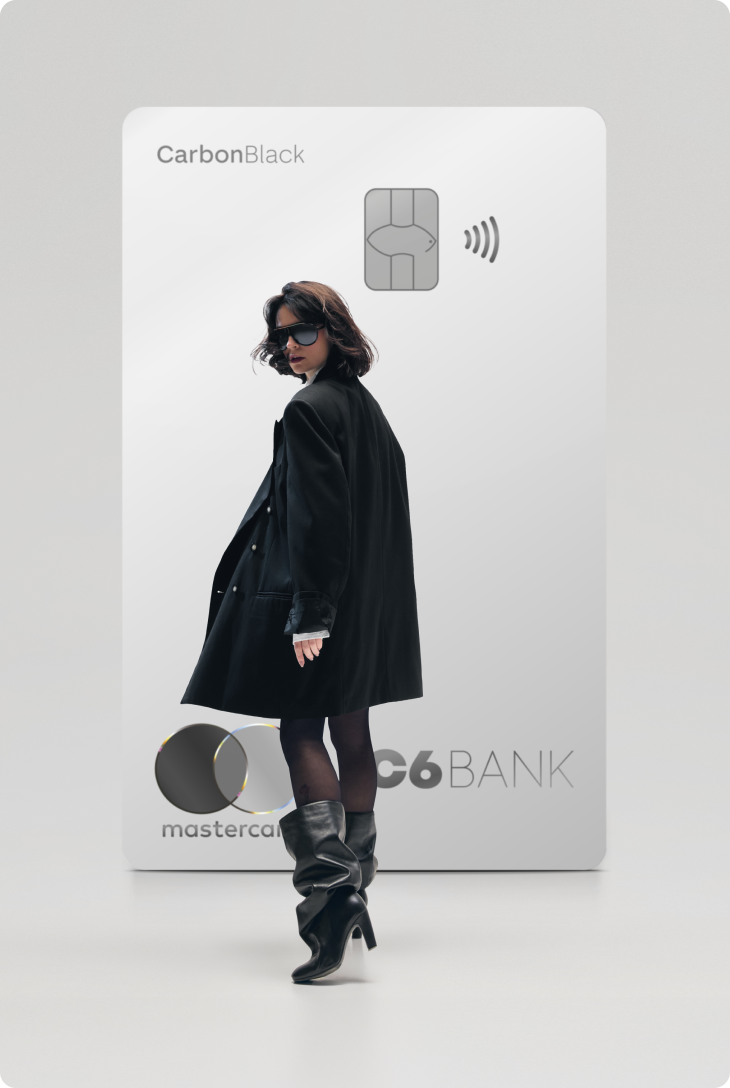 Mulher de preto caminha à frente de um Cartão C6 Carbon Mastercard Black prata em tamanho ampliado, sobre fundo claro.