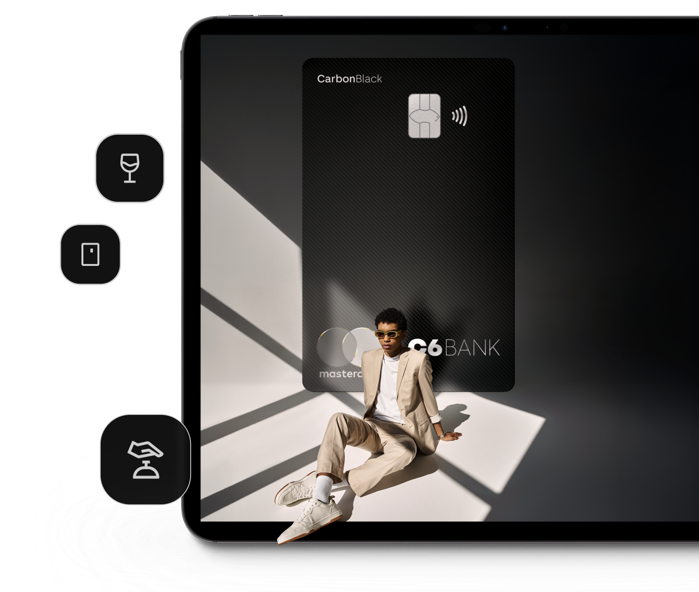 Tela de tablet com homem negro sentado em frente ao cartão gigantes C6 Carbon Mastercard Black.