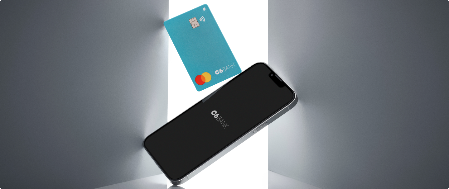 Benefícios C6 Bank Desktop Fotografia de celular e cartão C6 Bank na cor Acqua, no meio de duas paredes cinzas