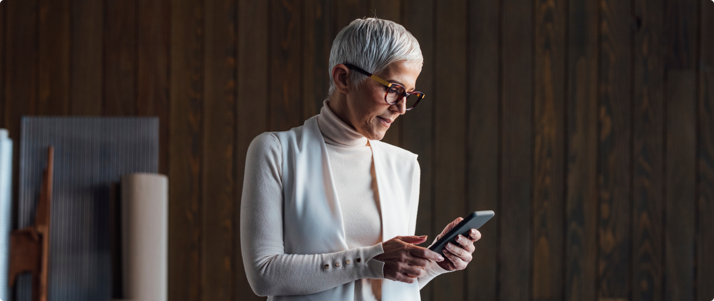 Foto de mulher de meia idade de óculos e cabelo curto branco segurando um celular