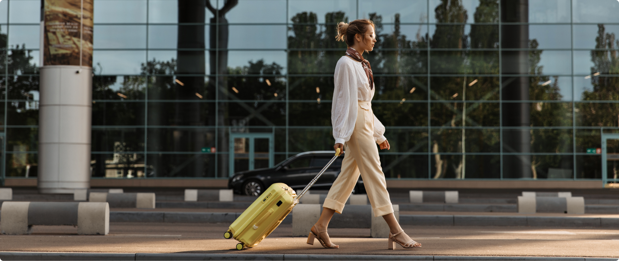 Foto de mulher loira caminhando em um aeroporto puxando uma mala de rodinhas amarela