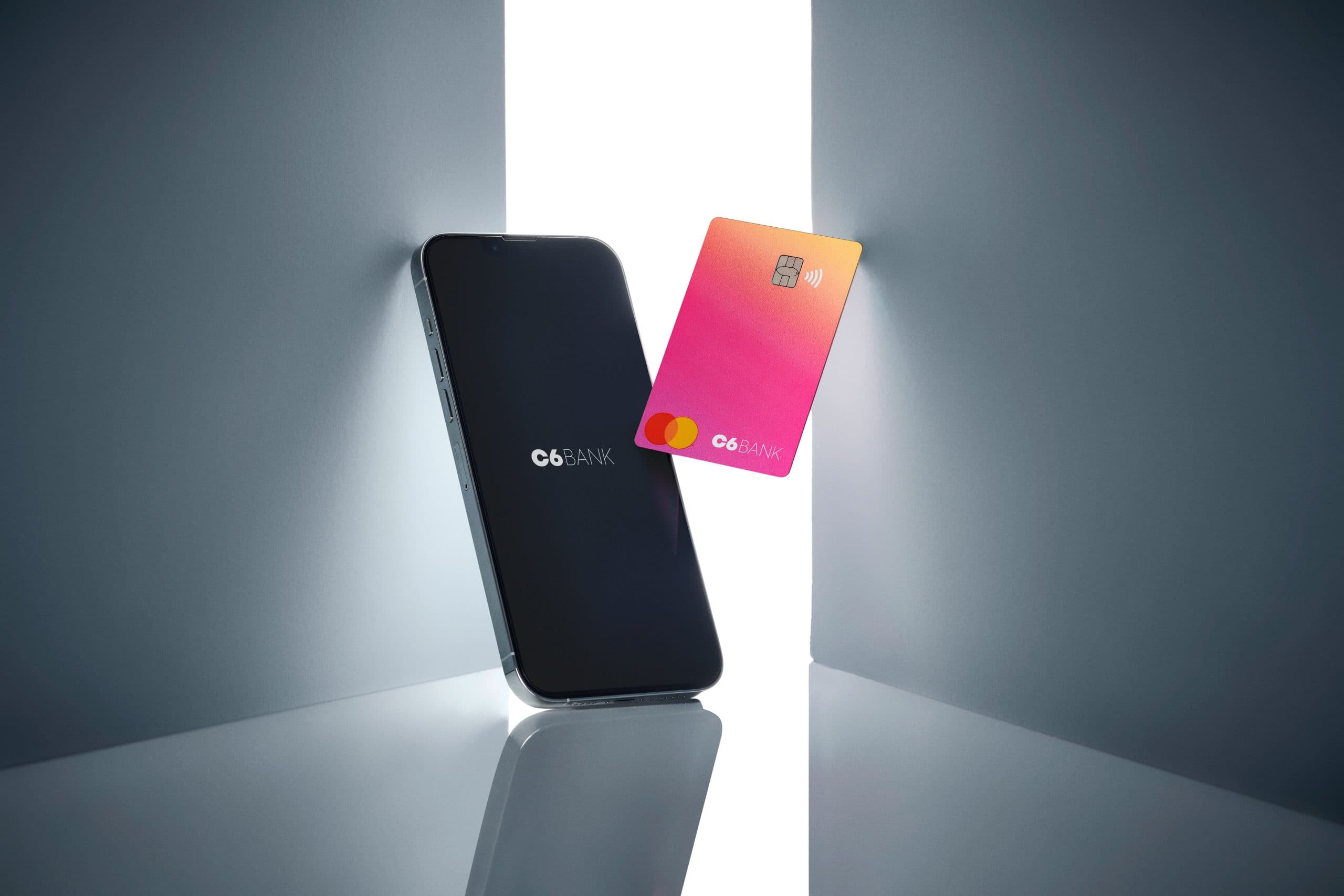 Celular com app C6 Bank aberto e cartão C6 Bank Sunset