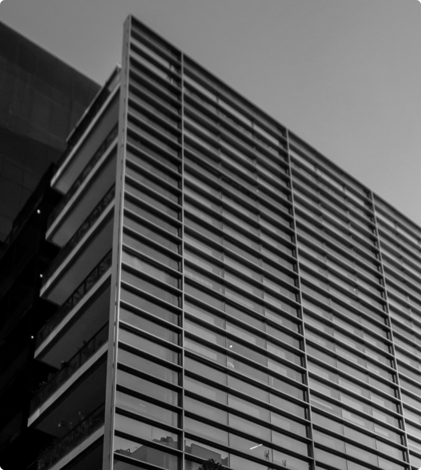 Sede C6 Bank: Prédio moderno em preto e branco com linhas horizontais e céu ao fundo.