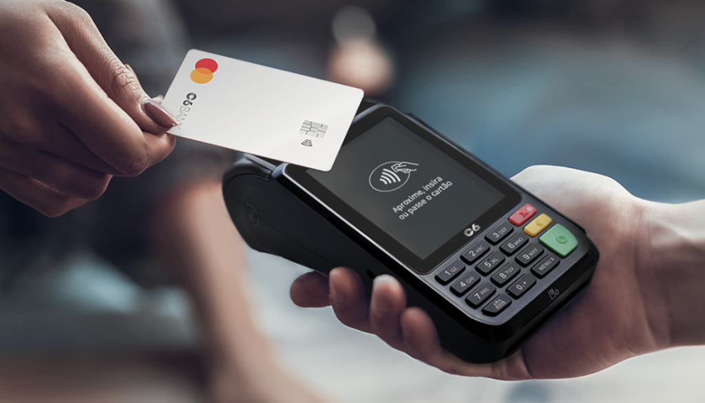 Imagem mostra pessoa fazendo pagamento por aproximação em maquininha C6 Pay com cartão C6 Bank prata