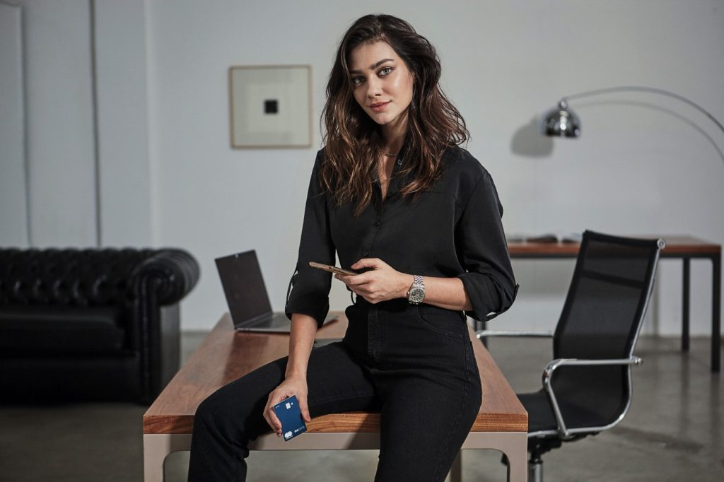 CSixer sentada em mesa enquanto utiliza o app do banco