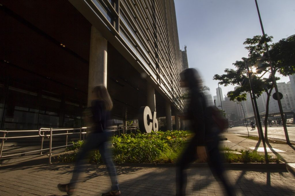 Foto da entrada do prédio do C6 Bank com colaboradores entrando no banco
