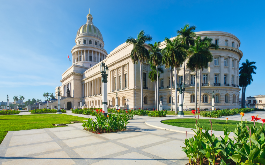 Imagem do Capitolio de Havana, Cuba, mostrando sua arquitetura neoclássica e jardins bem cuidados.