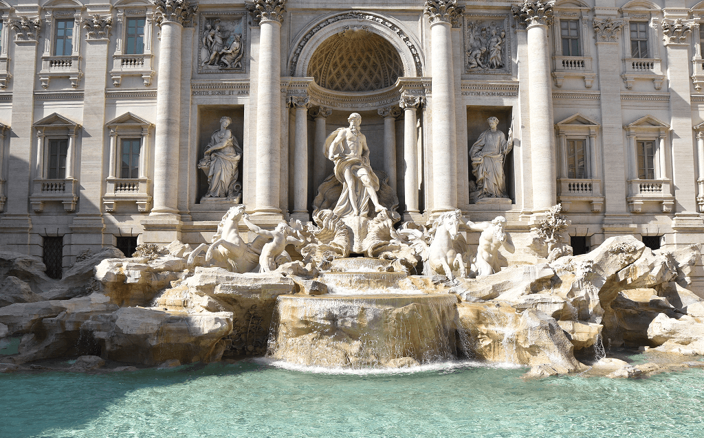 Fontana di Trevi em Roma, com esculturas monumentais de Netuno e tritões em meio a um cenário barroco, emolduradas por uma fachada de palácio de pedra clara.