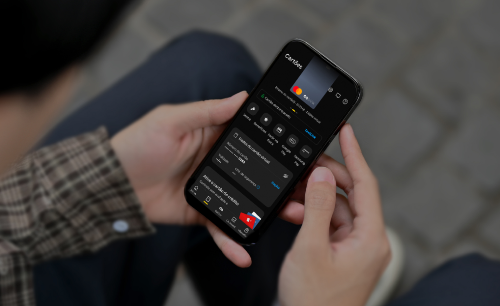 Imagem de uma pessoa segurando um celular aberto no app do C6 Bank na tela de bloqueio do cartão de crédito.