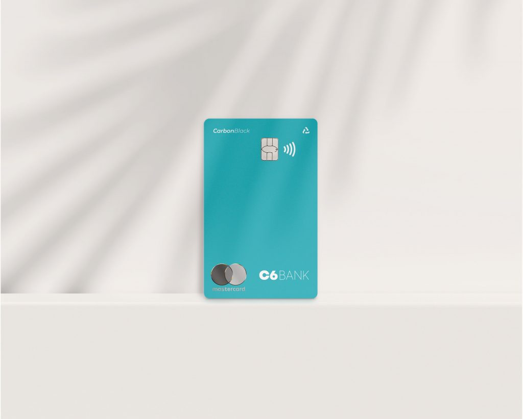 Foto do cartão Acqua, um cartão azul piscina, com o logo da Mastercard, logo do C6 Bank, a inscrição &quot;Carbon Black&quot;, o chip, o sinal de NFC e o sinal de &quot;retornável&quot;, posicionado em pé, em um fundo branco com efeito de movimento.