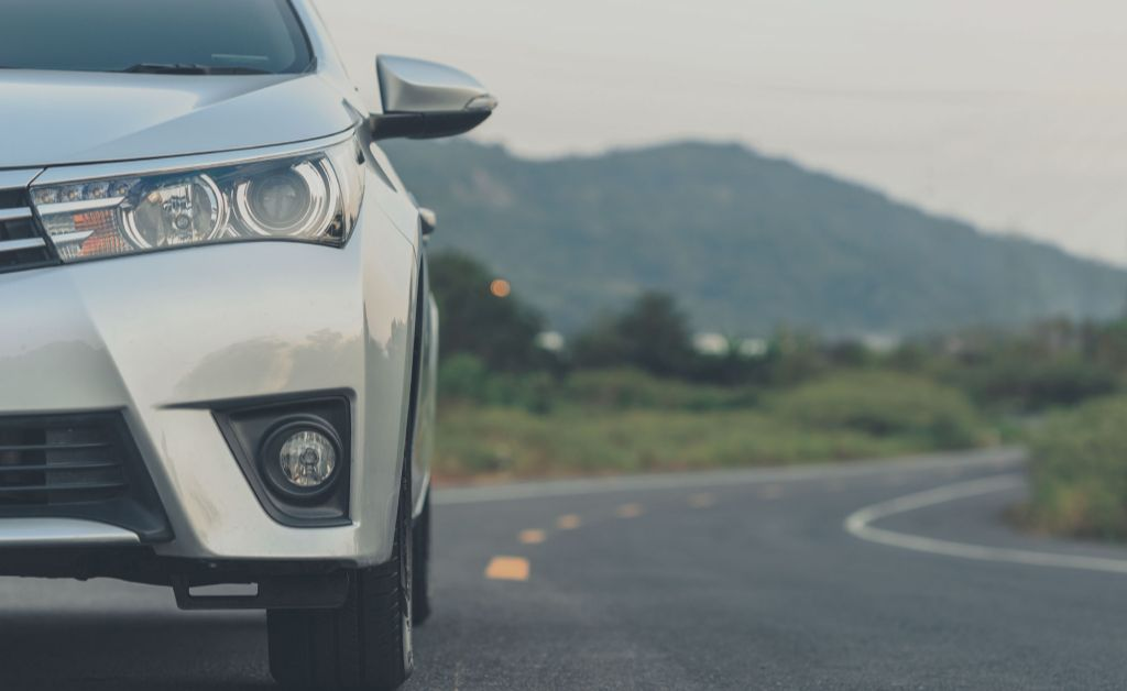 c6 consorcio  frente de uma suv prata em uma estrada