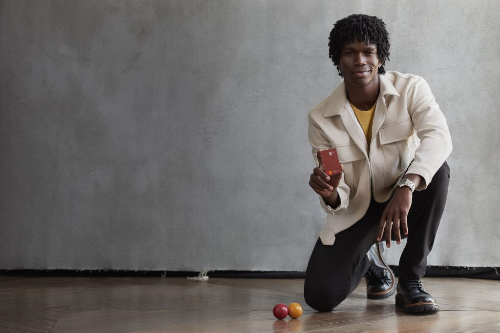 Foto de um homem negro, segurando um cartão do C6 Bank, pensando nos pontos Átomos