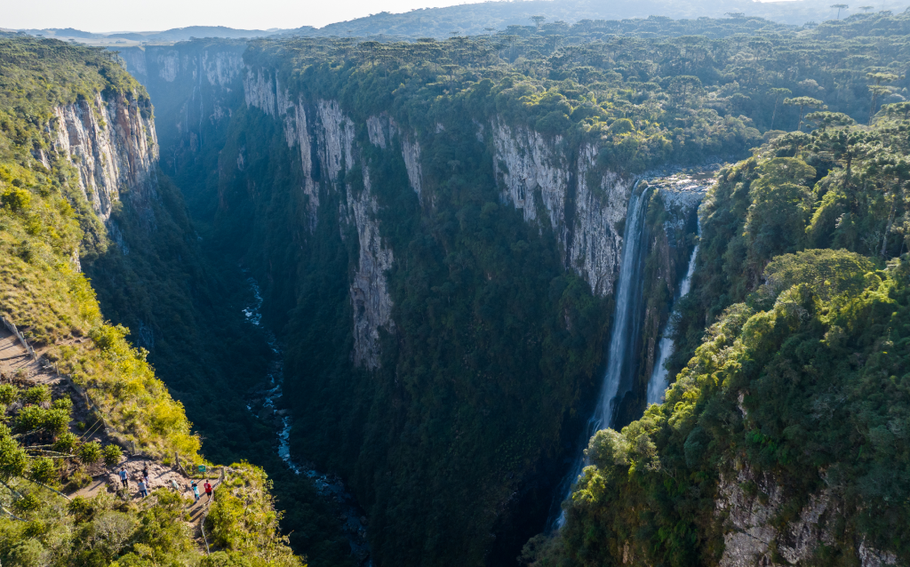 Vista deslumbrante do Parque Nacional do Itaimbezinho, destacando a majestosa queda d'água que se precipita em um cânion profundo e verdejante, ideal para ecoturismo.