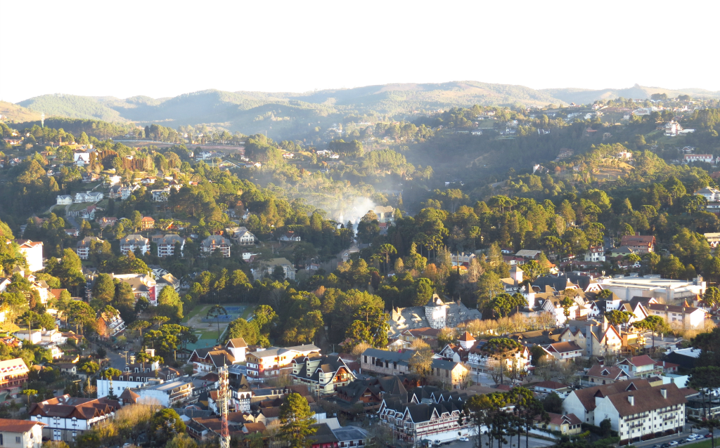 Vista panorâmica da cidade com montanhas ao fundo, mostrando casas e vegetação, ideal para apreciar a beleza natural da região.