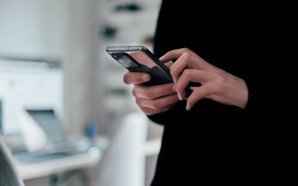 Mulher mexendo no celular, pesquisando como abrir conta em dólar no Brasil