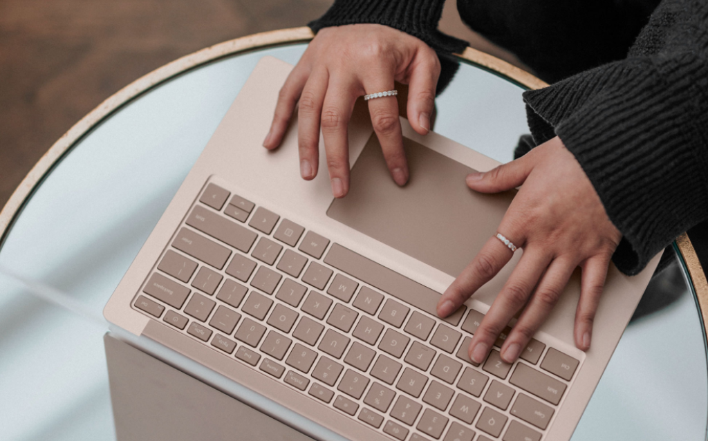 Mulher pesquisando em computador rosa como ganhar dinheiro dormindo com dividendos