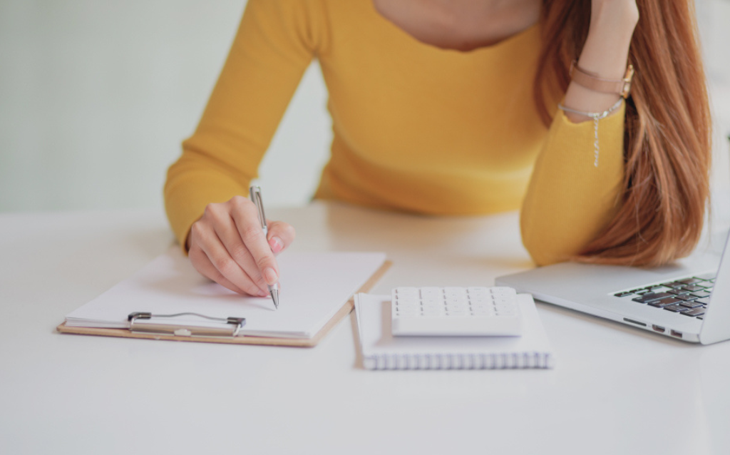 Mulher escrevendo em um papel e pesquisando sobre como gerar link de pagamento