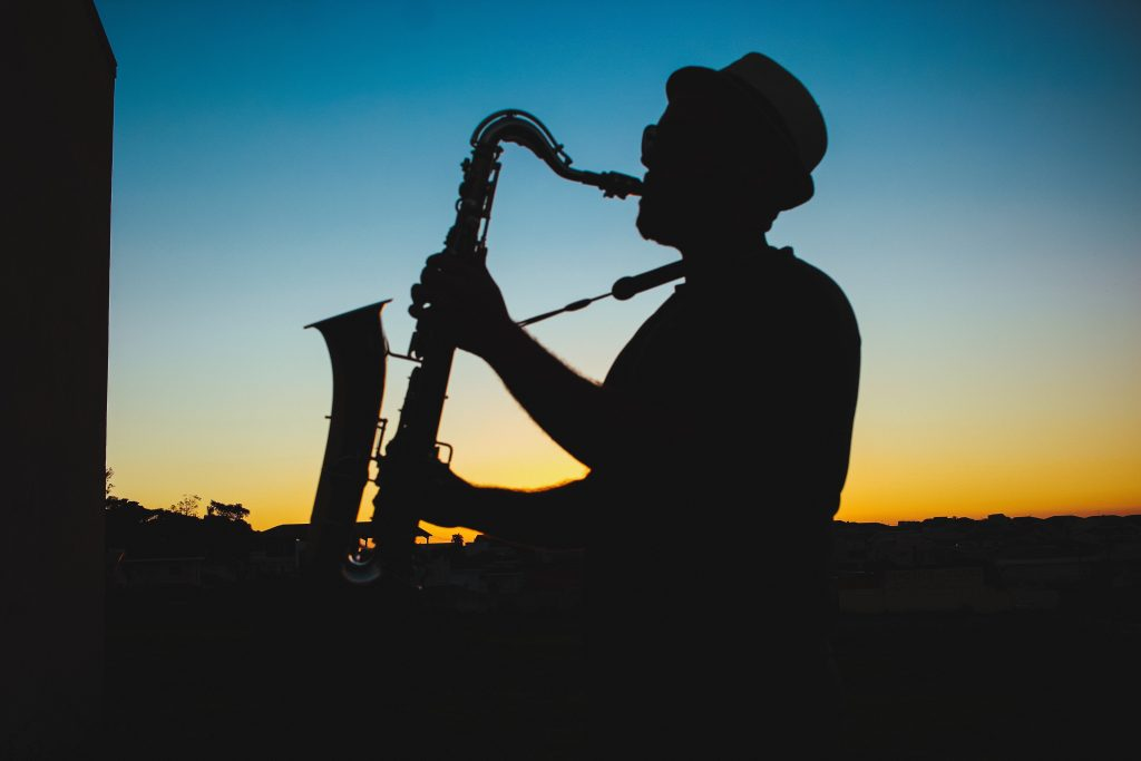 imagem de homem tocando instrumento de jazz contra o por do sol