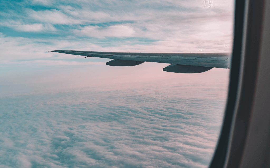 vista da janela do avião para o céu azul com nuvens simbolizando programa de milhas